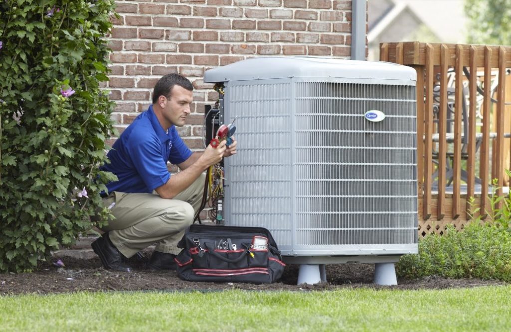 air conditioning maintenance; man servicing AC unit