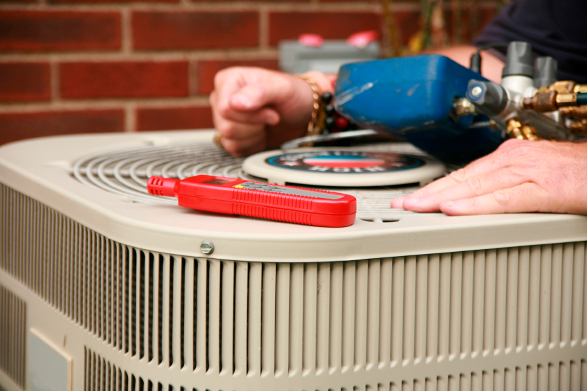 close-up of hands on outdoor heating and ac unit making repairs