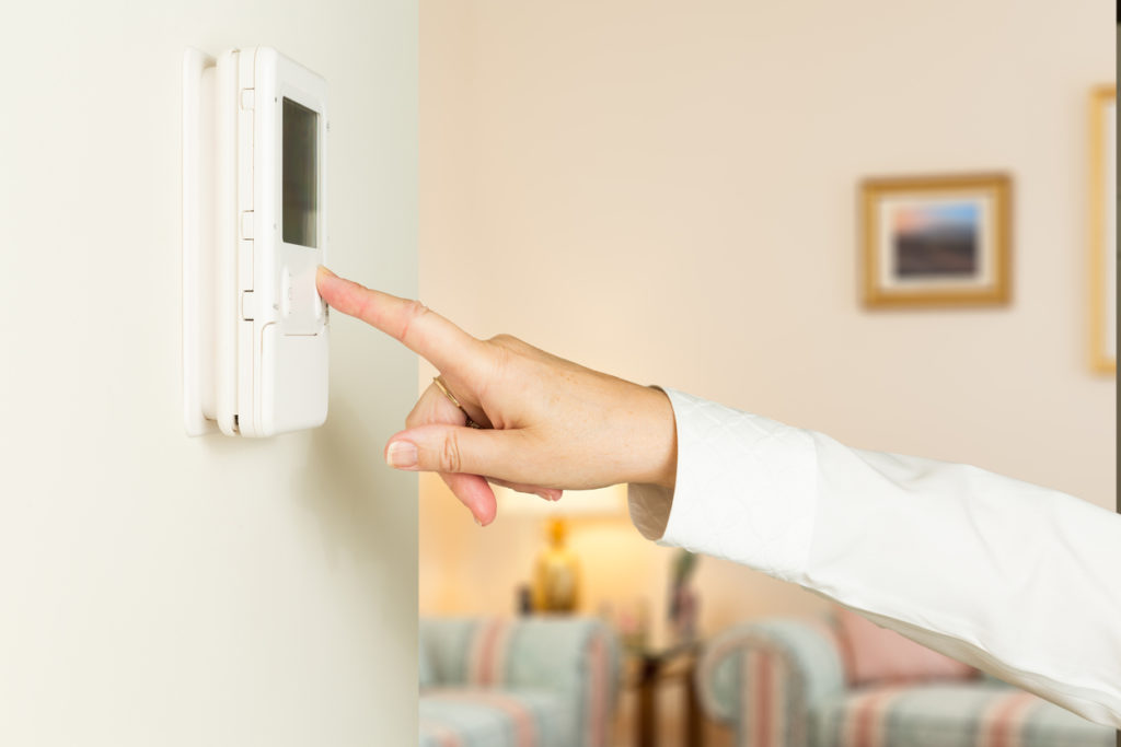 Caucasian lady pressing modern thermostat
