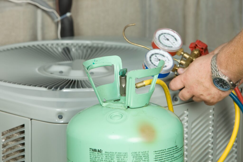 Hands of a male AC technician as he is recharging refrigerant levels